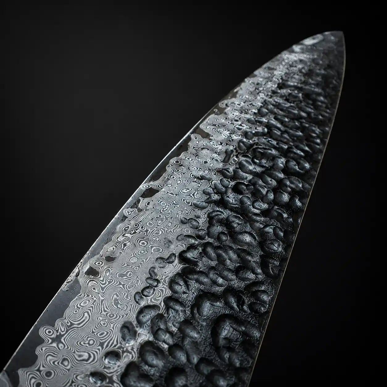 Close-up of a Damascus steel knife blade with a dark background